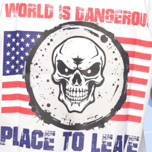 Deadly skull design layered over the American flag with bold text: “World is Dangerous, Place to Leave.” A rebellious, dark message warning of chaos with intense, gritty energy