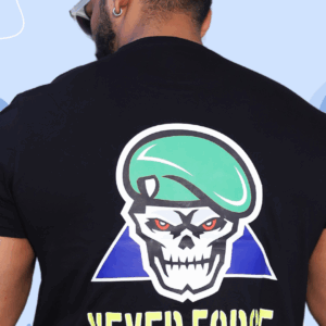 A bold T-shirt design featuring a skull-faced military figure in a green beret with fierce red eyes, symbolizing strength and warning. The phrase “NEVER FORCE” reflects his silent code—respect is earned, not commanded