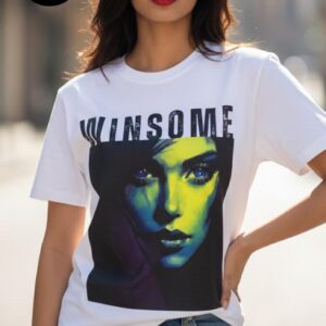 A woman in a white T-shirt stands facing away, showing the back design which features the bold word “WINSOME” above a stylish rectangular graphic in muted tones, set against a neutral concrete background