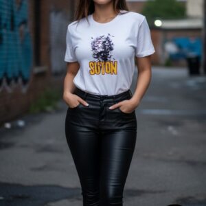 A stylish woman stands confidently in an urban setting, wearing a white T-shirt featuring a striking graphic of a detailed face surrounded by bold dark brushstrokes, with the creative word “SUTON” in vibrant yellow below, symbolizing individuality and expressive spirit