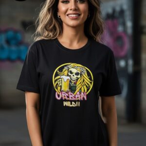 A stylish black T-shirt featuring a vibrant graphic of a woman with long, flowing blonde hair adorned with white daisies, holding a frothy mug of beer, set against a bold yellow circular background. Below the artwork, the bold and playful text reads “URBAN WILD!!” in pink and yellow, reflecting a lively, free-spirited urban vibe