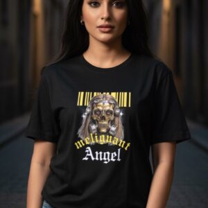 A confident Indian woman stands in an atmospheric urban alley, wearing a black T-shirt featuring a striking design of a golden skull with long hair, metal details, and a barcode above, with bold text reading “malignant Angel” in yellow and white gothic fonts, blending edgy style with urban elegance